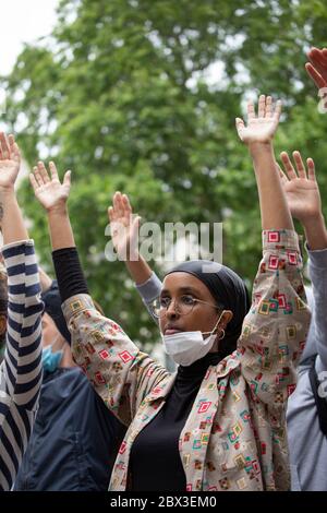 Ein junges ethnisches Mädchen, das während des Black Lives Matters Protestes vor der Downing Street 10, London, 3. Juni 2020, das Knie ergraut und die Hände hebt Stockfoto