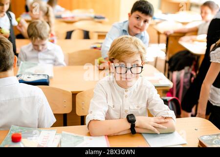 Wenig Erstlingssortierer, Mädchen-Schüler geht auf Wissen Tag zur Schule - September zuerst. Schüler der Grundschule in Uniform mit Bogen in der Klasse posing Stockfoto