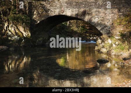 Alte Steinbrücke über Great Langdale Beck in Elterwater Dorf, Lake District, Großbritannien Stockfoto