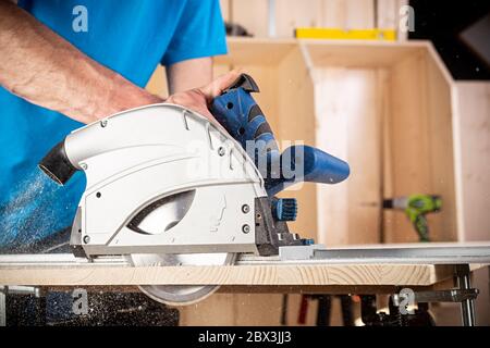 Tischler mit Hand Kreissäge bei der Arbeit. Nahaufnahme von Sägen einen Schnitt aus Kiefernholz Holzbearbeitung Bau-Tool-Konzept Möbel machen diy Hintergrund Stockfoto