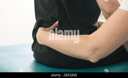 Physiotherapeut, der mit behinderten Menschen auf einem Behandlungstisch trainiert. Stockfoto