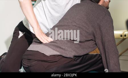 Physiotherapeut, der mit behinderten Menschen auf einem Behandlungstisch trainiert. Stockfoto