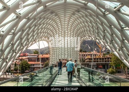 7-19-2019 Tiflis Georgien - die Brücke des Friedens - eine bogenförmige Fußgängerbrücke aus Stahl und Glas, beleuchtet mit zahlreichen LEDs über dem Kura Rive Stockfoto