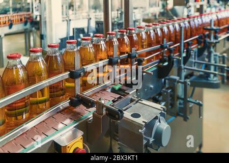 Getränkeherstellung, Herstellung von Lebensmitteln und Getränken, Flaschen mit Saft auf Förderband. Stockfoto