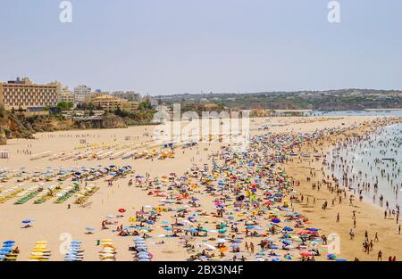 Blick auf den Strand Praia da Rocha in Portimao mit Sonnenliegen, Liegen und Sonnenschirmen im Sommer, Westalgarve, Südportugal Stockfoto