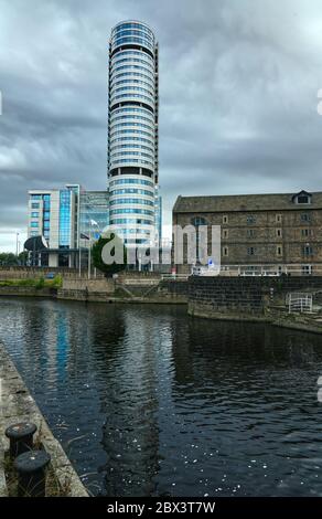 Leeds, Großbritannien - 07. Juli 2019: Moderne Geschäftsgebäude in der Nähe von Vintage-Fabrikgebäude unter dem trüben regnerischen Himmel. Stockfoto