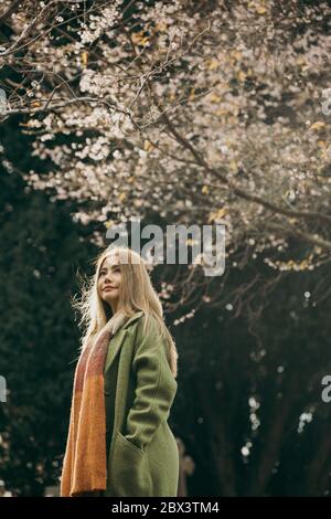 Asiatische Frau mit neuseeländischen Kirschblüten oder Sakuras im frühen Herbst vor dunklem Hintergrund. Stockfoto