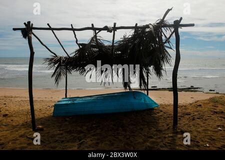 Wunderschöner, farbenfroher Strand Praia do Forte, Bahia, Blick durch Strohhütte und Fischerboot auf dem Sand. Gerahmte Einsamkeit. Reisen Stockfoto