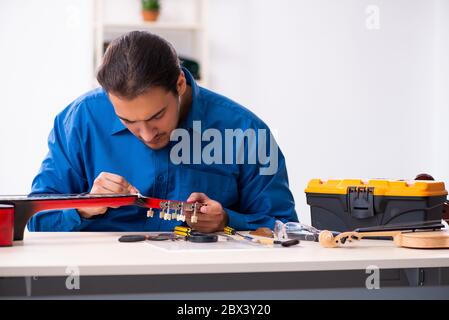 Junger Mann Reparatur der Gitarre Stockfoto