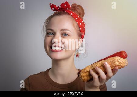 Lächelnd junge kaukasische Frau Mädchen hält einen Hotdog. Konzept für die Lebensmittelzustellung Stockfoto