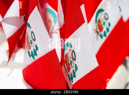 Kleine peruanische Flaggen zum Verkauf am Nationalfeiertag, Cusco, Peru. Das zentrale Wappen mit Vicuna, Cinchona-Baum und Füllhorn mit Münzen verschüttet. Stockfoto