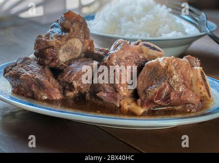 Nahaufnahme, Makrofotografie von Rippen in Austernsauce mit einem Teller Reis am Boden, asiatisches Speisekonzept Stockfoto