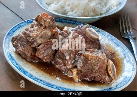 Nahaufnahme, Makrofotografie von Rippen in Austernsauce mit einem Teller Reis am Boden, asiatisches Speisekonzept Stockfoto