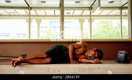 Ein Obdachloser schläft am Bahnhof Hua Lamphong im Zentrum der Stadt im Bezirk Pathum Wan. Stockfoto