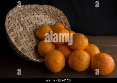 Stillleben, Low-Key oder dunkle Food-Fotografie, Orangen in einem Korb auf einem Tisch Stockfoto