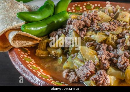 Mexikanische Küche, Picadillo-Fleisch mit Gemüse, Zwiebeln, Paprika und Zucchini, mit einem Teller Knoblauch-Reis auf der Seite, serrano-Chili und Mais-Tortillas. Stockfoto