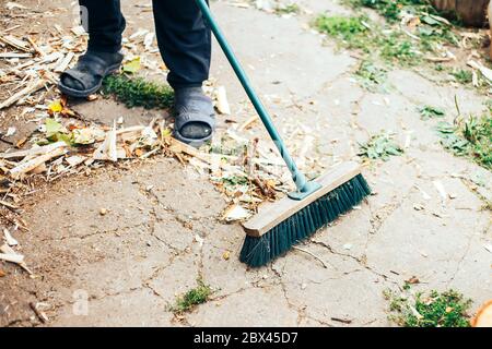 Alte Besen und Metallkelle mit Müll in den Händen von Männern Arbeitshandschuhe Stockfoto