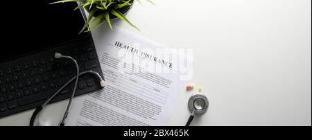 Life Planning Konzept mit Krankenversicherungsform, Stethoskop, digitalen Tabletten und Medizin auf weißem Schreibtisch in der Draufsicht Stockfoto