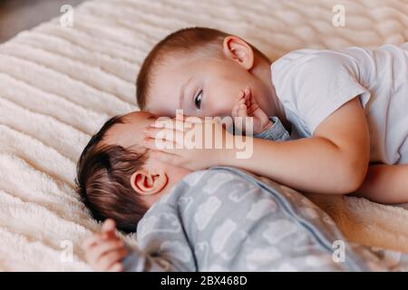 Der Bruder und seine fröhliche kleine Schwester, die auf dem Bett liegt, gähnt Stockfoto