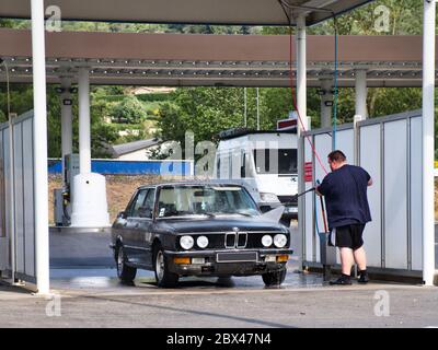 Mann, der die Lanze benutzt, um sein Auto bei einer Waschanlage mit Schaum zu sprühen. Stockfoto