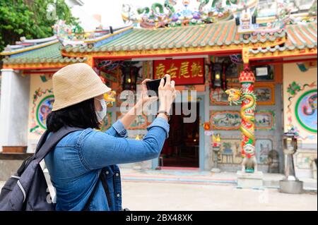 Asiatische Tourist in einer chirurgischen Gesichtsmaske Bilder am chinesischen Tempel in Bangkok Stockfoto