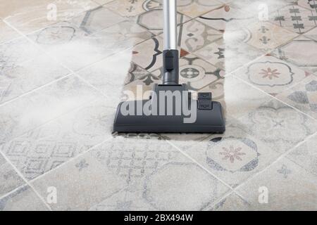 Reinigen und Entfernen von Staub mit modernen Staubsauger im Küchenraum. Konzept der einfachen Reinigung mit Zyklonsauger Stockfoto