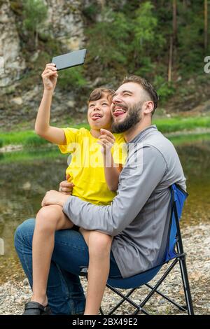 Portrait des lustigen Vaters und seines Sohnes, der Selfie im Freien macht. Stockfoto