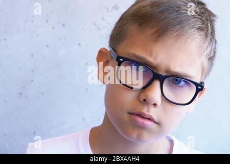 Smart besorgt Jungen mit Auge blaues Licht blockiert Brille Blick auf Kamera. Grunge grauen Hintergrund Wand Stockfoto