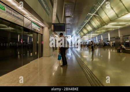 Singapur - 07. Juli 2017: Nicht identifizierter Mann mit Rucksack, der Smartphone spielt, während er auf den MRT-Zug wartet, der zur Plattform in Singapur kommt. Stockfoto