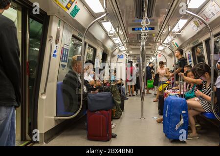 SINGAPUR - 07. JULI 2017: Unbekannte Passagiere in einem überfüllten Mass Rapid Transit (MRT) U-Bahn-Zug Ankunft an der City Hall-Station in den Geschäftsleuten Stockfoto
