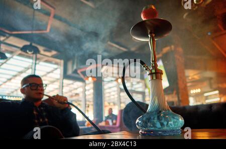 Ein Mann raucht eine Shisha in einem dunklen Raum Stockfoto
