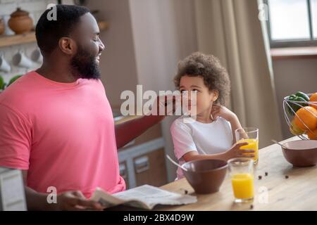 Dunkelhaariger afroamerikanischer Vater berührt seine Töchter Wange und lächelt Stockfoto