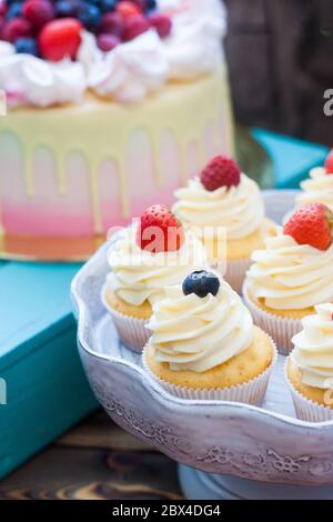 Vanillekuchen mit Frischkäse-Zuckerguss und frischen Beeren, Heidelbeere und Erdbeere. Rustikaler Hintergrund. Stockfoto