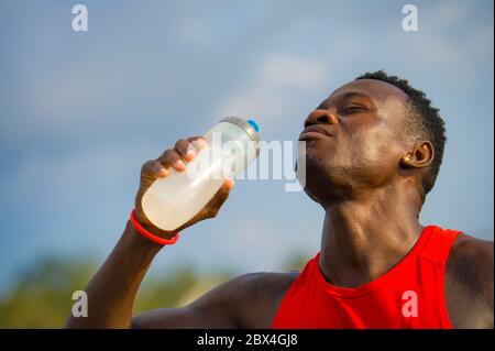 Junge schöne und attraktive schwarz afro amerikanischen Sportmann müde und durstig nach dem Laufen Training hält Flasche Trinkwasser oder isotonische Energie d Stockfoto