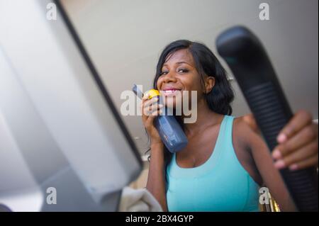 Drinnen Fitness-Studio Porträt von jungen attraktiven und glücklich schwarz afro amerikanische Frau Training elliptische Maschine Training im Fitness-Club lächelnd fröhlich drin Stockfoto