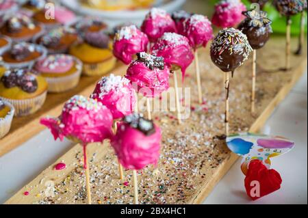 Köstliche rosa und Schokolade Kuchen Pops auf Holzschreibtisch warten auf Kinder. Stockfoto