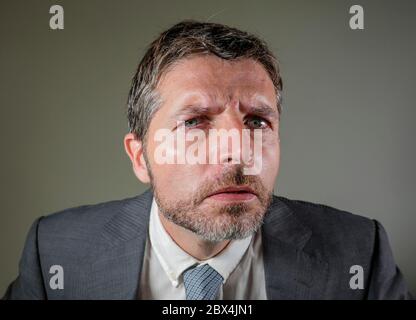 Nahaufnahme Gesicht Porträt von jungen wütend und unglücklich Geschäftsmann in Anzug und Krawatte suchen ernst und neugierig posiert bossy und cool, als ob fragen oder Stockfoto