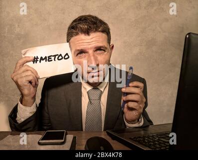Junge depressive und frustrierte Geschäftsmann verzweifelt im Büro Computer Schreibtisch halten Notizblock mit dem Hashtag mich zu metoo als ausgebeuteten Mitarbeiter victi Stockfoto