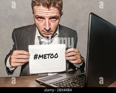 Junge depressive und frustrierte Geschäftsmann verzweifelt im Büro Computer Schreibtisch halten Notizblock mit dem Hashtag mich zu metoo als ausgebeuteten Mitarbeiter victi Stockfoto