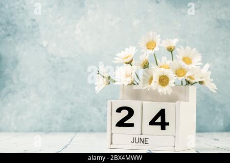 Weißer Würfel Kalender für juni mit Gänseblümchen Blumen auf blauem Hintergrund mit Kopierraum dekoriert Stockfoto