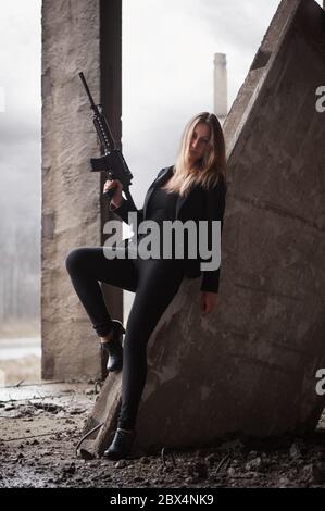 Frau mit Maschinengewehr in einem verlassenen Gebäude Stockfoto