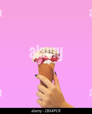 Eiscreme-Kegel auf rosa Hintergrund. Die Frau, die das Eis von Hand hält Stockfoto