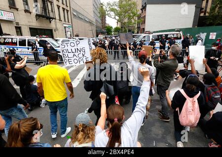 New York, NY, 2. Juni 2020. Die Leute halten kurz an einer verbarrikadierten Wohnstraße an und knien und heben Fäuste in der Luft auf die helmeted Polizei; zwei Leute halten auch ein "Stop Töten schwarzer Menschen" Zeichen. Die Menschen marschieren in Solidarität mit anderen im ganzen Land und rufen in einer Reihe von amerikanischen Polizeimorden Gerechtigkeit an: George Floyd, Breonna Taylor und zahllosen anderen. Tausende von Menschen schlossen sich dem marsch vom Foley Square an und stoppten in der Nähe von Gracie Mansion, dem Haus des New Yorker Bürgermeisters, bevor sie später am Abend zum Times Square umgezogen waren. Juni 2020 Stockfoto