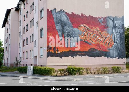 05. Juni 2020, Baden-Württemberg, Mannheim: Ein Wandgemälde des Mannheimer Graffiti-Künstlers Rick Riojas zeigt ein Motiv eines Mädchens, das die Hand eines älteren Menschen auf der façade eines Hauses im Stadtteil Schönau hält. Dazwischen ist der Schriftzug "Family is everything" aufgesprüht. Riojas-Kunstwerke, die auf Häuser des Mannheimer Wohnungsbauverbandes GBG angewendet werden, werden erst für einen bestimmten Zeitraum bis zur Sanierung der Gebäude ausgestellt. Foto: Uwe Anspach/dpa - ACHTUNG: Nur für redaktionelle Verwendung im Zusammenhang mit einem Bericht über Wandmalereien an Hausfassaden der Mannheimer Wohnungsbaugesellschaft GBG Stockfoto