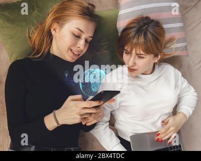 Frauen verbinden und teilen mit sozialen Medien, Scrollen Smartphone. Interaktives Globenmodell. Moderne UI-Symbole, Kommunikation, Geräte. Konzept der modernen Technologien, Vernetzung, Gadgets. Design. Stockfoto