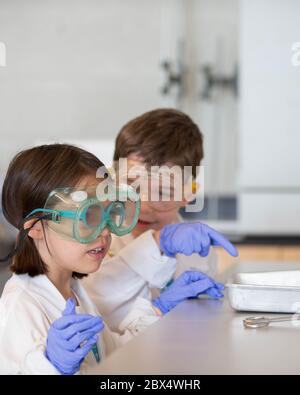 Junge Studenten, die ein wissenschaftliches Experiment in einem Chemielabor durchführen! Sie haben ihre Laborkittel und Schutzbrille an, Sicherheit geht vor! Stockfoto