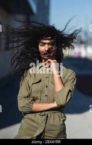 Junge attraktive Frau mit ihrem welligen Haar im Wind Stockfoto