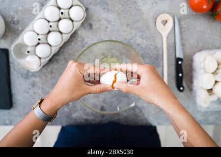 Frau Kochen Zu Hause In Küche Zerbrechen Ei Stockfoto