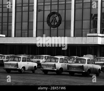 Berliner Bezirke / Ende der DDR / Emblem / 20.2.1985 Ost-Berlin: Palast der Republik. Es gab auch die Volkskammer. Das DDR-Emblem hängt noch immer dort. Der davor abgehngte Parkplatz zeigt den Wohlstand der DDR. Es gab hauptsächlich nur 2 Typen von Autos: Trabant und Wartburg. Der Palast wurde nach der Vereinigung abgerissen. // DDR-Staat / Linden anstelle des 1950 abgerissenen Stadtpalastes wurde ab 1973 das Schloss der Republik gebaut, 180 m lang, 32 m breit. Im Inneren waren verschiedene Einrichtungen. In der großen Halle, die 5000 Besucher hielt, fanden Veranstaltungen statt. Die Volkskammer der DDR Stockfoto