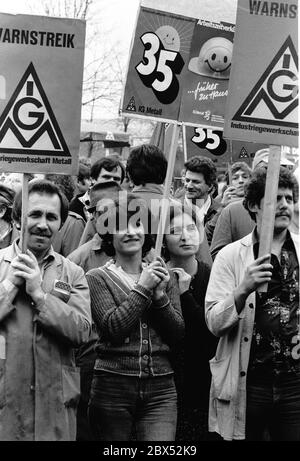 Berlin / Hochzeit / Türken / Ausländer 1983 Hochzeit: Proteste vor dem Fabriktor der AEG in der Brunnenstraße. Die AEG steht vor dem Konkurs, dieses Werk soll geschlossen werden. Die Mehrheit der Arbeitskräfte ist türkisch. Arbeiter verlassen die Förderbänder und kommen zu der Versammlung vor dem historischen Fabriktor. // Branche / Geschichte. 1888 baute AEG in Wedding an der Ackerstraße einen großen Industriekomplex, der bald zu klein wurde. Es übernahm ein noch größeres Grundstück in der Voltastraße. Die riesigen Fabriken produzierten fast alles, was AEG verkaufte: Kleine Motoren und riesige Turbinen, Licht Stockfoto